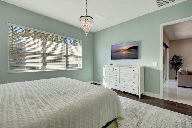 bedroom featuring multiple windows, wood finished floors, visible vents, and baseboards