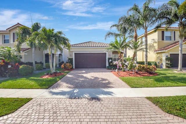 mediterranean / spanish-style home with decorative driveway, stucco siding, an attached garage, a front yard, and a tiled roof