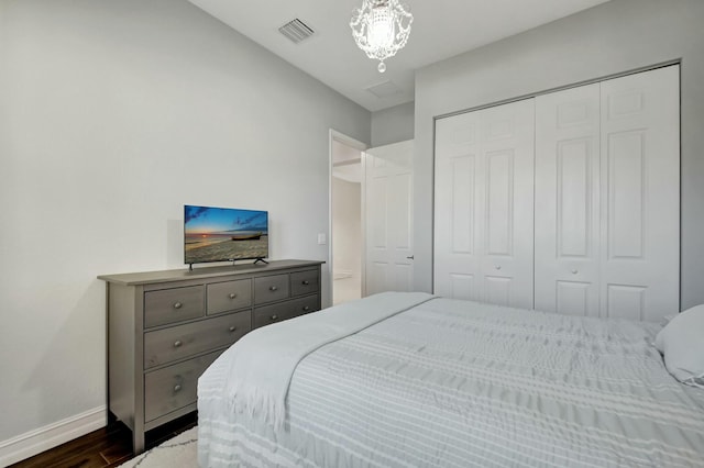 bedroom with dark wood-style flooring, visible vents, baseboards, a closet, and an inviting chandelier