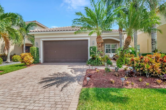 view of front of home with an attached garage, a tiled roof, decorative driveway, and stucco siding