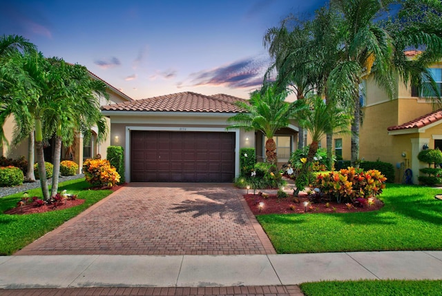 mediterranean / spanish-style home featuring an attached garage, a tile roof, decorative driveway, and stucco siding