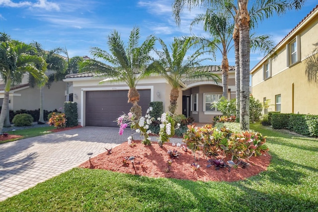 view of front of house with stucco siding, a tile roof, an attached garage, decorative driveway, and a front yard