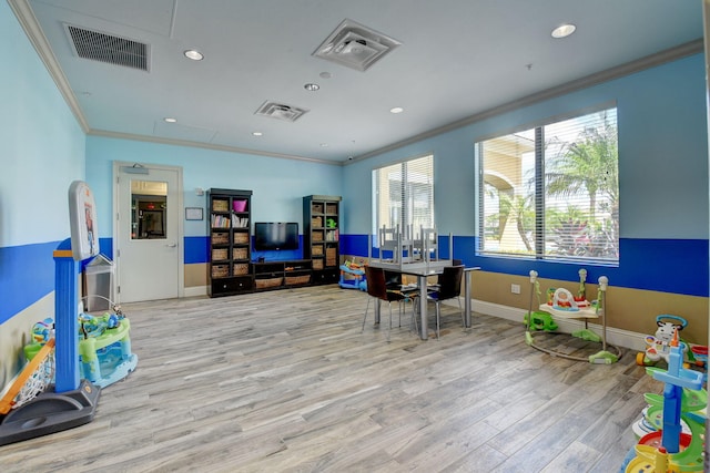 rec room with ornamental molding, visible vents, baseboards, and wood finished floors