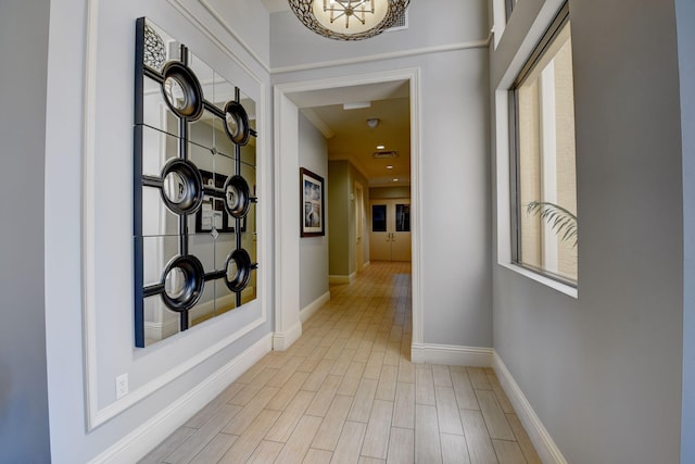 corridor featuring light wood-style flooring and baseboards