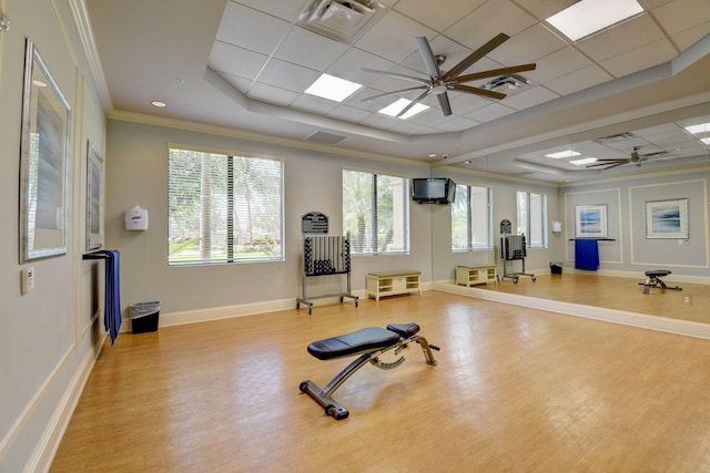 exercise area with wood finished floors, visible vents, a ceiling fan, a raised ceiling, and crown molding