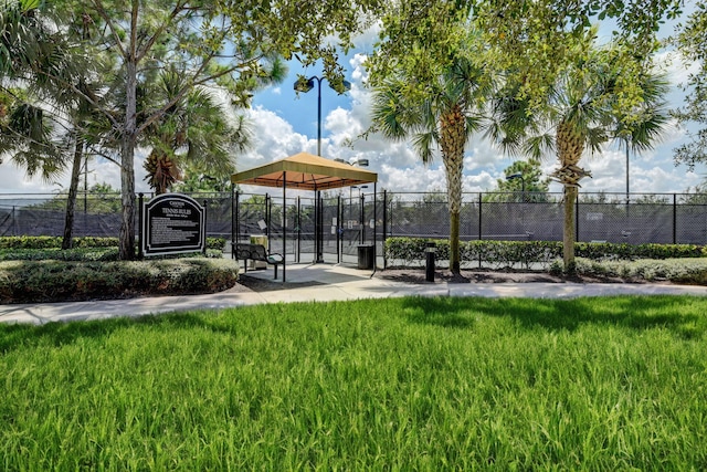 view of property's community featuring a gate, fence, and a lawn