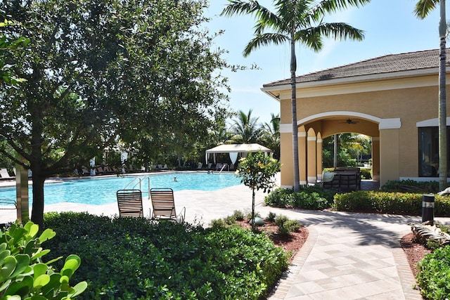 community pool with ceiling fan and a patio