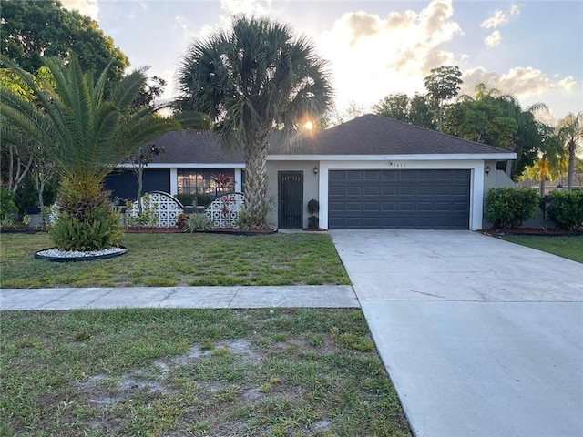 single story home with driveway, a front lawn, an attached garage, and stucco siding