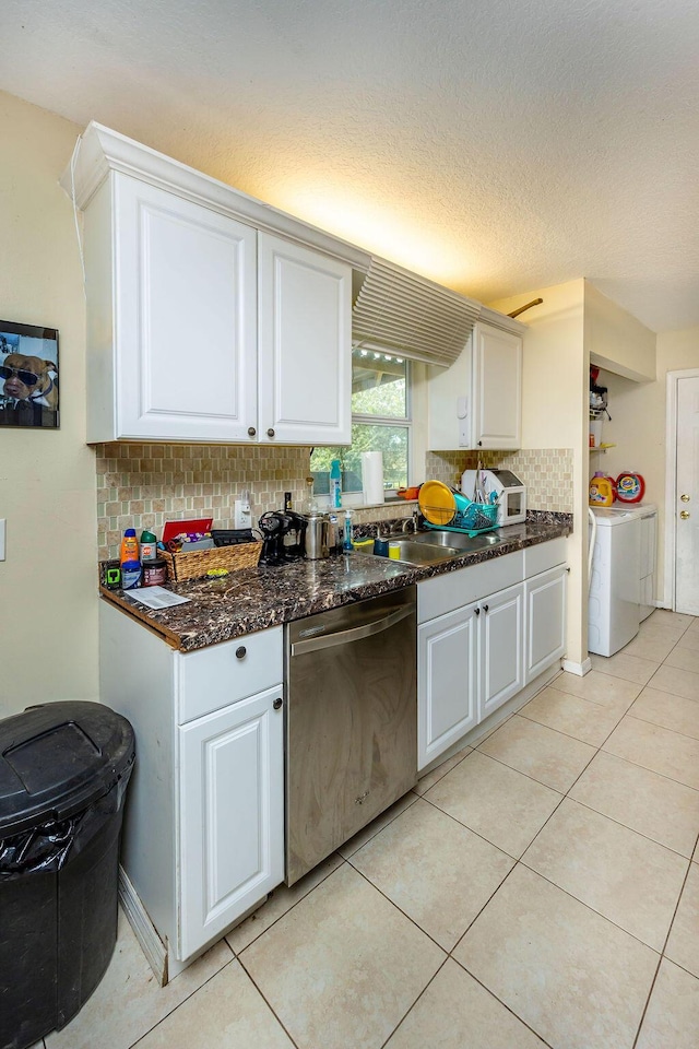 kitchen with separate washer and dryer, stainless steel dishwasher, a sink, and white cabinets