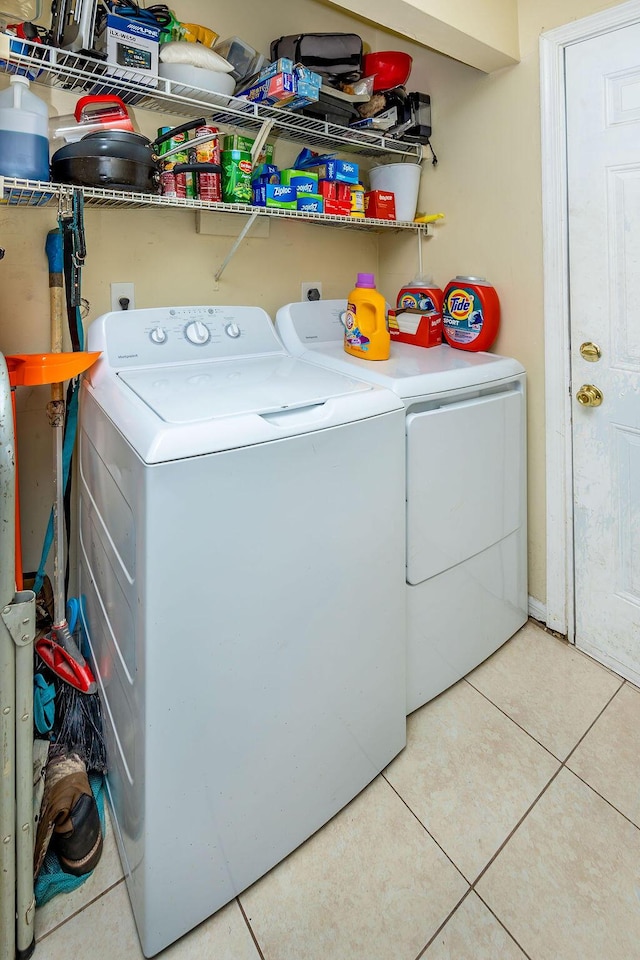 clothes washing area featuring laundry area, washing machine and clothes dryer, and light tile patterned floors