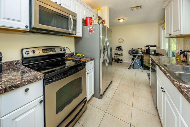 kitchen with light tile patterned flooring, a sink, visible vents, white cabinets, and appliances with stainless steel finishes