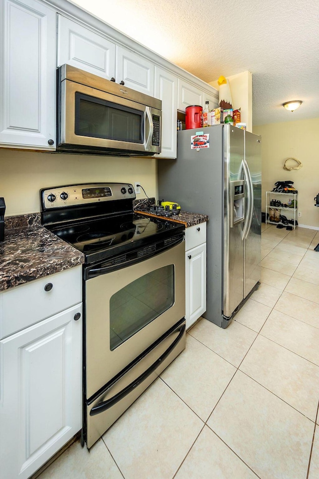 kitchen with appliances with stainless steel finishes, white cabinets, and light tile patterned flooring