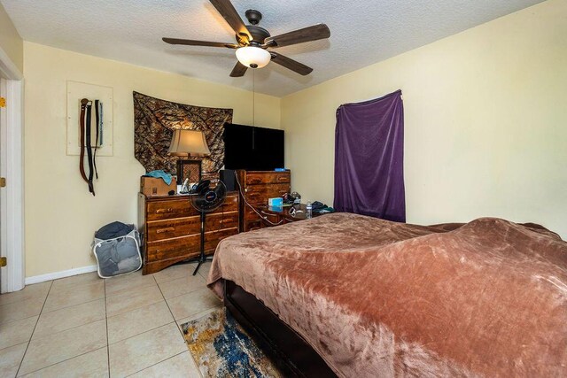 bedroom with light tile patterned floors, baseboards, a ceiling fan, and a textured ceiling