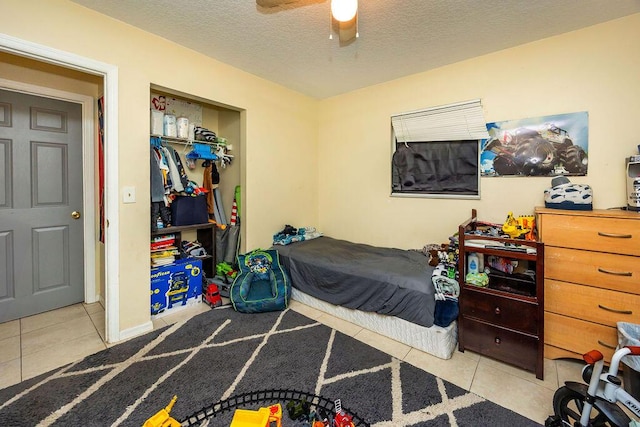 bedroom with a ceiling fan, tile patterned flooring, a closet, and a textured ceiling