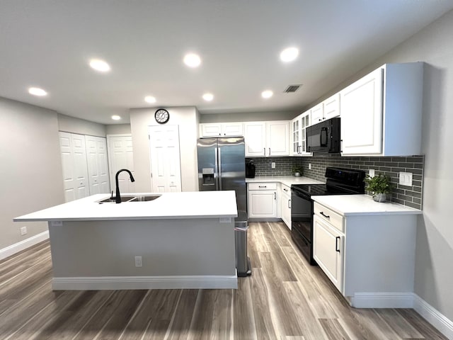 kitchen featuring light countertops, a sink, black appliances, and white cabinetry