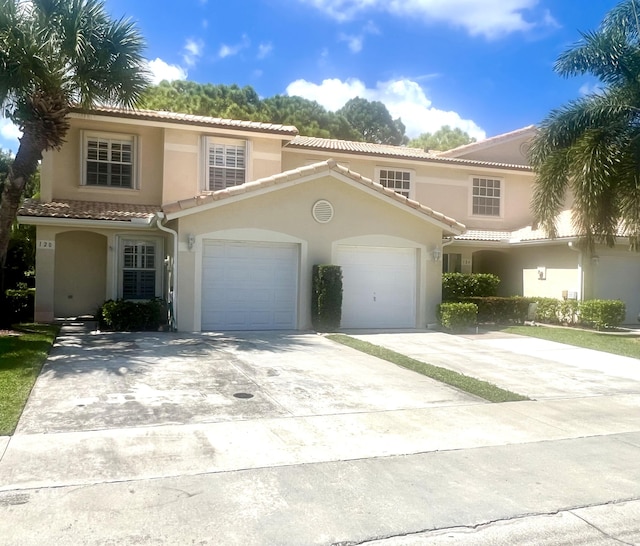 mediterranean / spanish home with a garage, driveway, and stucco siding