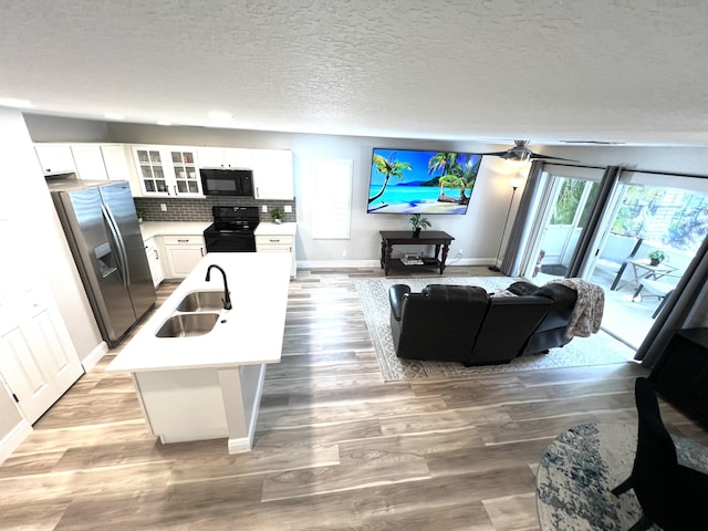 living area featuring light wood-style floors, ceiling fan, a textured ceiling, and baseboards