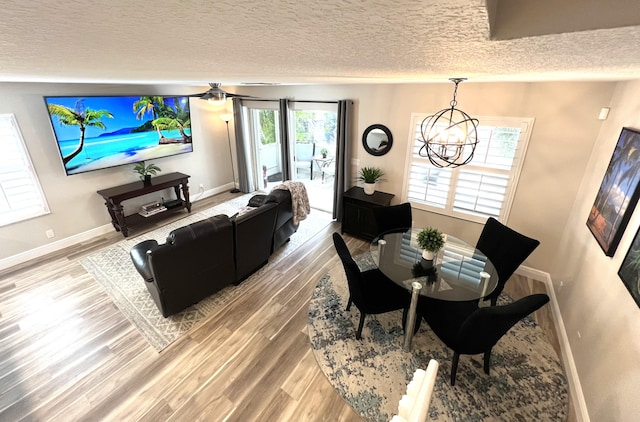 dining area featuring a textured ceiling, an inviting chandelier, wood finished floors, and baseboards