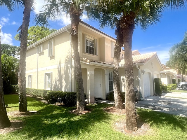 mediterranean / spanish house featuring a garage, driveway, a front lawn, and stucco siding