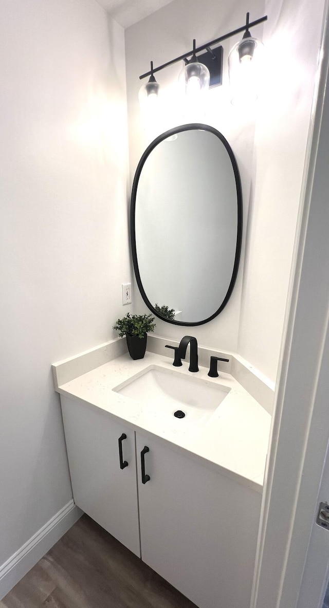 bathroom featuring baseboards, wood finished floors, and vanity