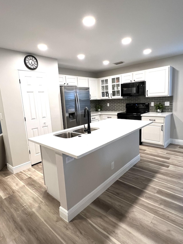 kitchen featuring black appliances, light countertops, glass insert cabinets, and white cabinetry