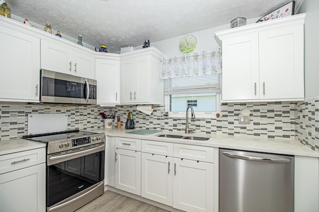 kitchen featuring stainless steel appliances, light countertops, a sink, and white cabinetry