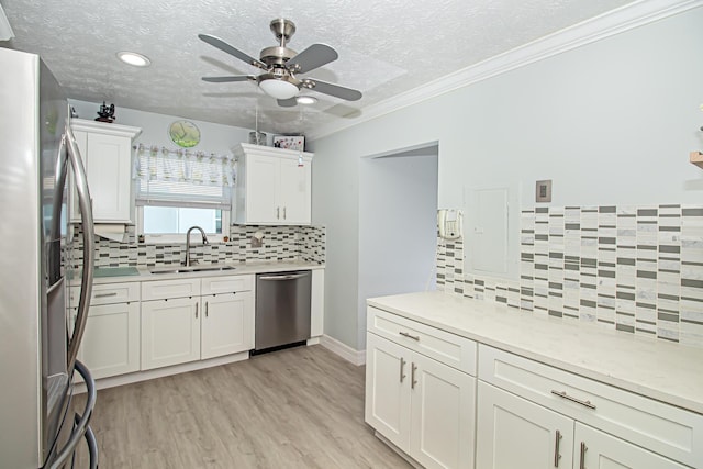 kitchen featuring stainless steel appliances, a sink, white cabinets, light countertops, and light wood finished floors