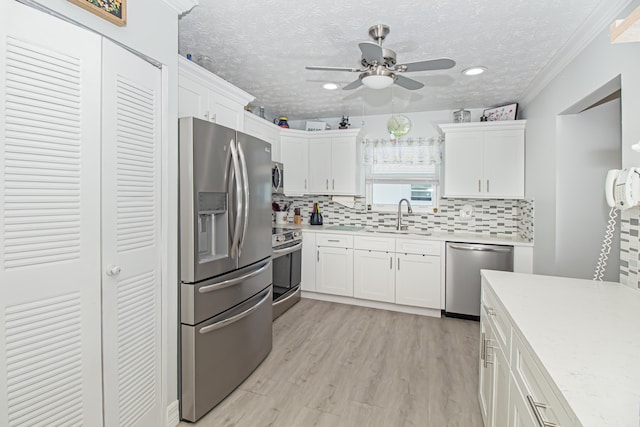 kitchen with stainless steel appliances, white cabinets, light countertops, and a sink