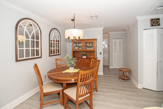 dining room with baseboards, crown molding, visible vents, and light wood finished floors