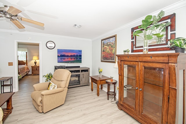 sitting room with ornamental molding, a ceiling fan, visible vents, and light wood-style floors