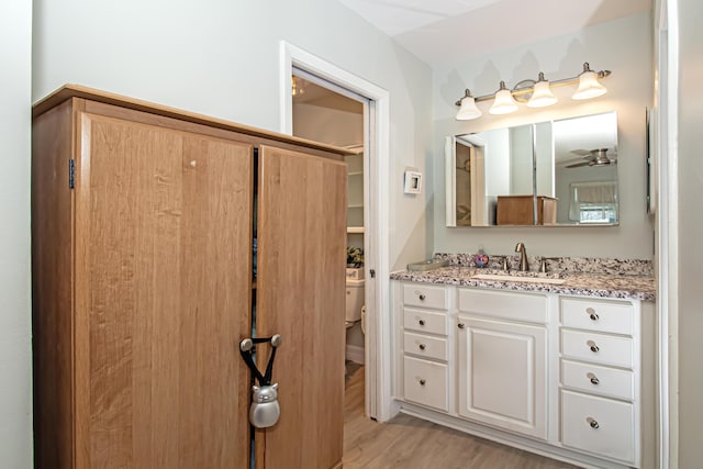 bathroom featuring ceiling fan, vanity, toilet, and wood finished floors