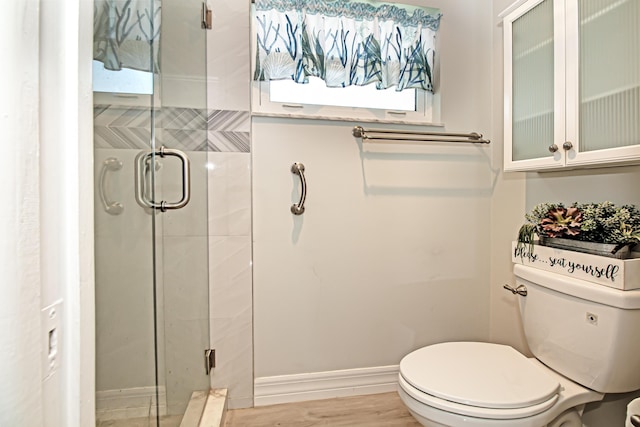 bathroom featuring toilet, a stall shower, baseboards, and wood finished floors