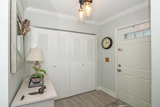 foyer entrance featuring baseboards, crown molding, and light wood finished floors