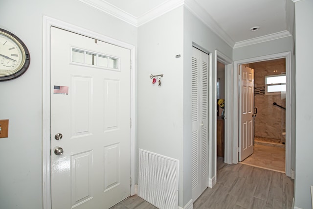 foyer entrance featuring visible vents, crown molding, light wood-style flooring, and baseboards