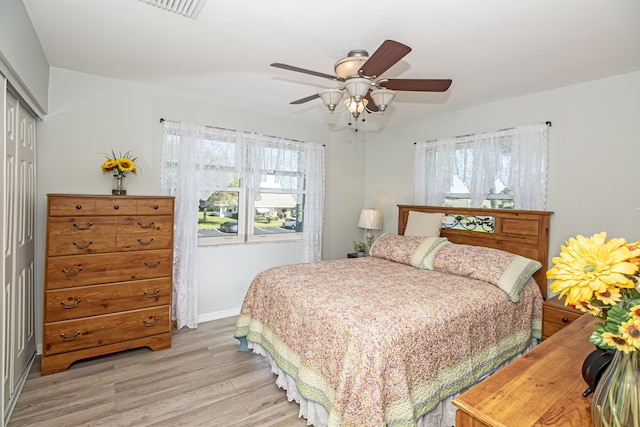 bedroom with baseboards, visible vents, a ceiling fan, light wood-style floors, and a closet