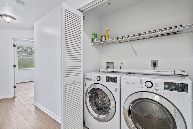 laundry room with a textured ceiling, washing machine and dryer, light wood-style flooring, laundry area, and baseboards