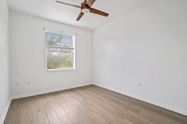 empty room with a ceiling fan, light wood-type flooring, a textured ceiling, and baseboards