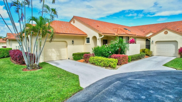 mediterranean / spanish house featuring concrete driveway, stucco siding, a tile roof, an attached garage, and a front yard