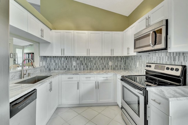 kitchen with light tile patterned floors, tasteful backsplash, appliances with stainless steel finishes, vaulted ceiling, and a sink