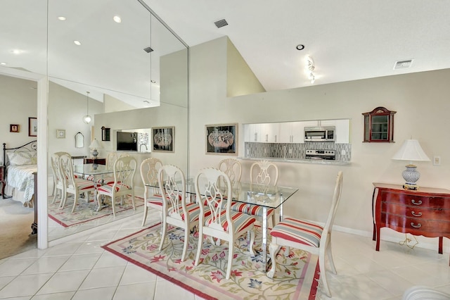 dining space with light tile patterned floors, high vaulted ceiling, and visible vents