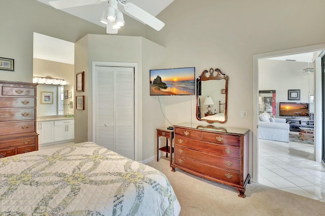 bedroom featuring a ceiling fan, a closet, light carpet, and ensuite bath