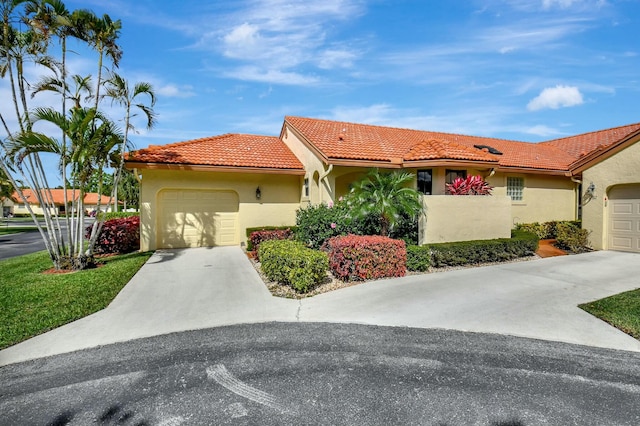 mediterranean / spanish-style home featuring a garage, a tiled roof, concrete driveway, and stucco siding