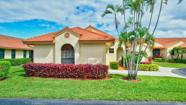 mediterranean / spanish home featuring driveway, a tiled roof, an attached garage, a front yard, and stucco siding