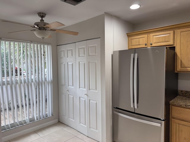 kitchen featuring visible vents, a ceiling fan, freestanding refrigerator, light tile patterned flooring, and light stone countertops