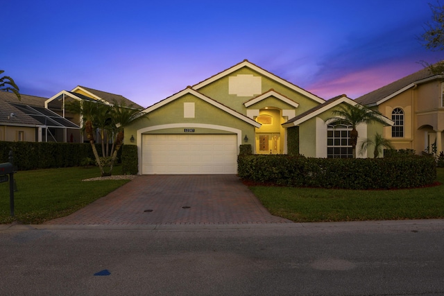 ranch-style home featuring a front lawn, decorative driveway, an attached garage, and stucco siding