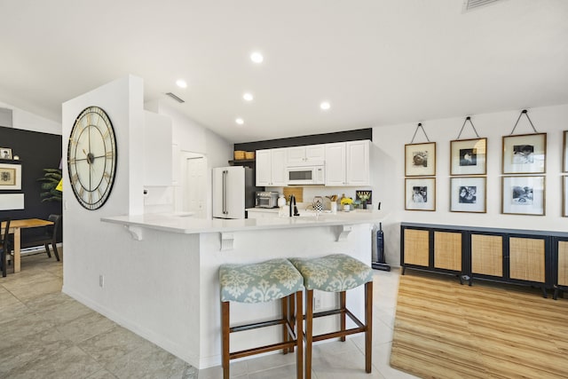 kitchen featuring white cabinets, a toaster, white appliances, lofted ceiling, and light tile patterned floors