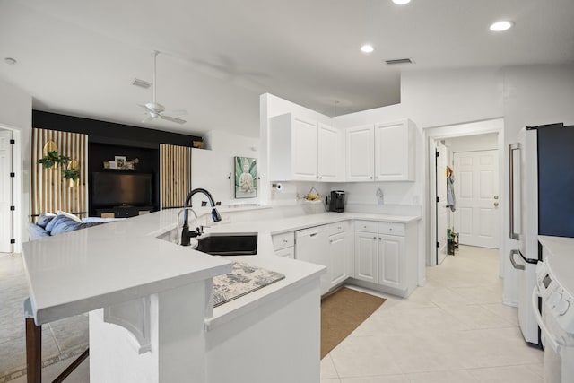kitchen featuring vaulted ceiling, a sink, light tile patterned floors, white appliances, and white cabinets