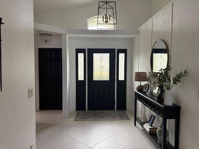 entryway with light tile patterned floors, vaulted ceiling, a notable chandelier, and a textured wall