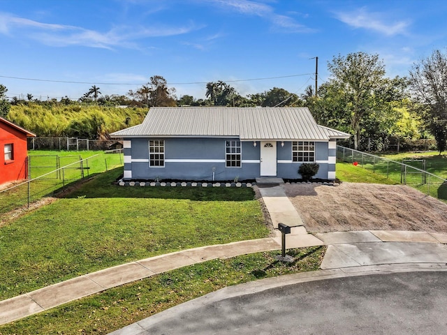 view of front of property with fence private yard, a front yard, metal roof, and stucco siding