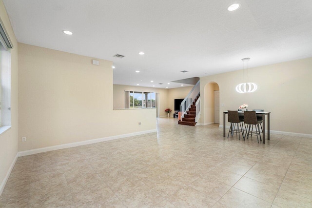 spare room with arched walkways, recessed lighting, visible vents, baseboards, and stairway